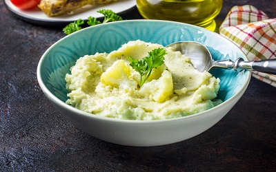 Cremiges Püree aus Blumenkohl, in einer blauen Schale angerichtet, appetitlich mit Petersilie dekoriert